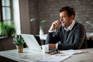 Male freelance worker reading an e-mail while working on laptop in the office.